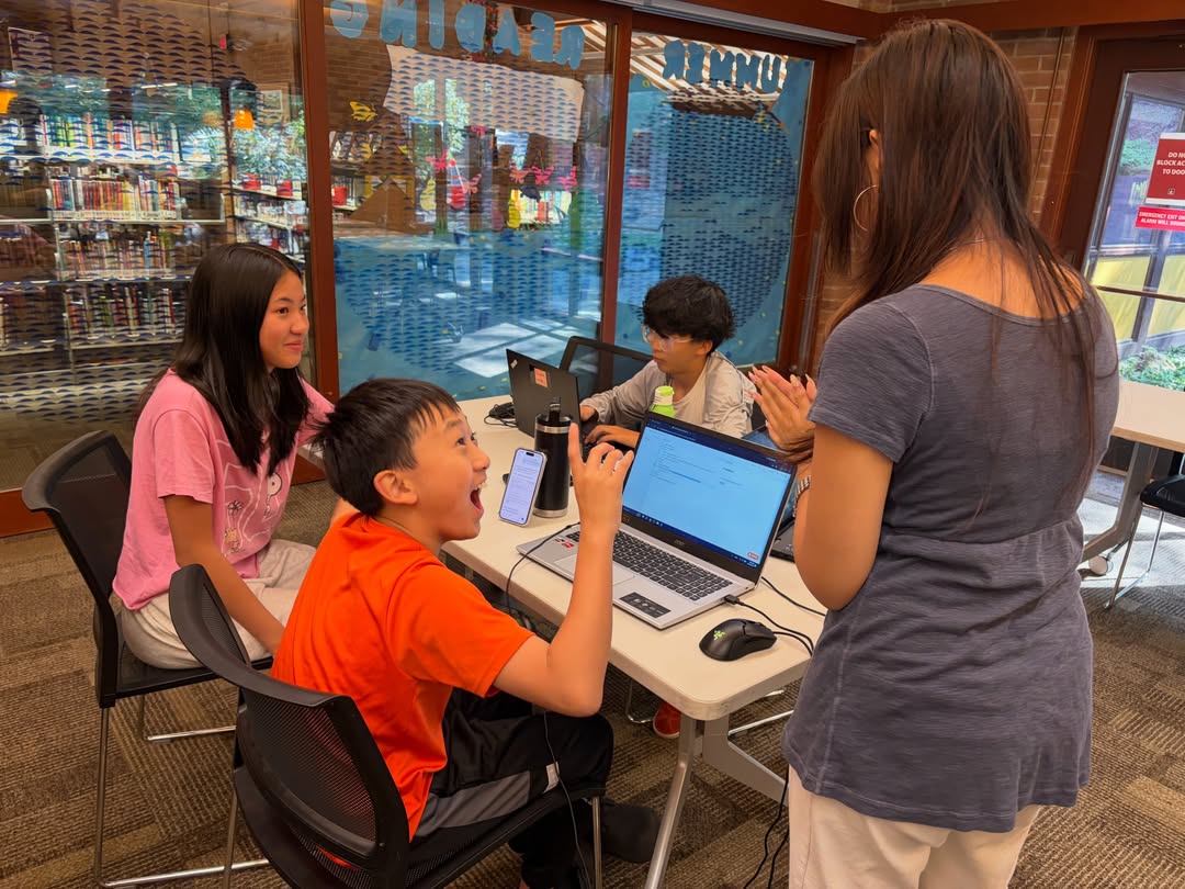 A student celebrating at a table full of laptops