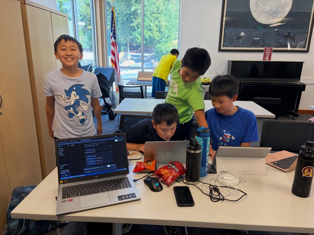 Four students with laptops and snacks, one grinning at the camera