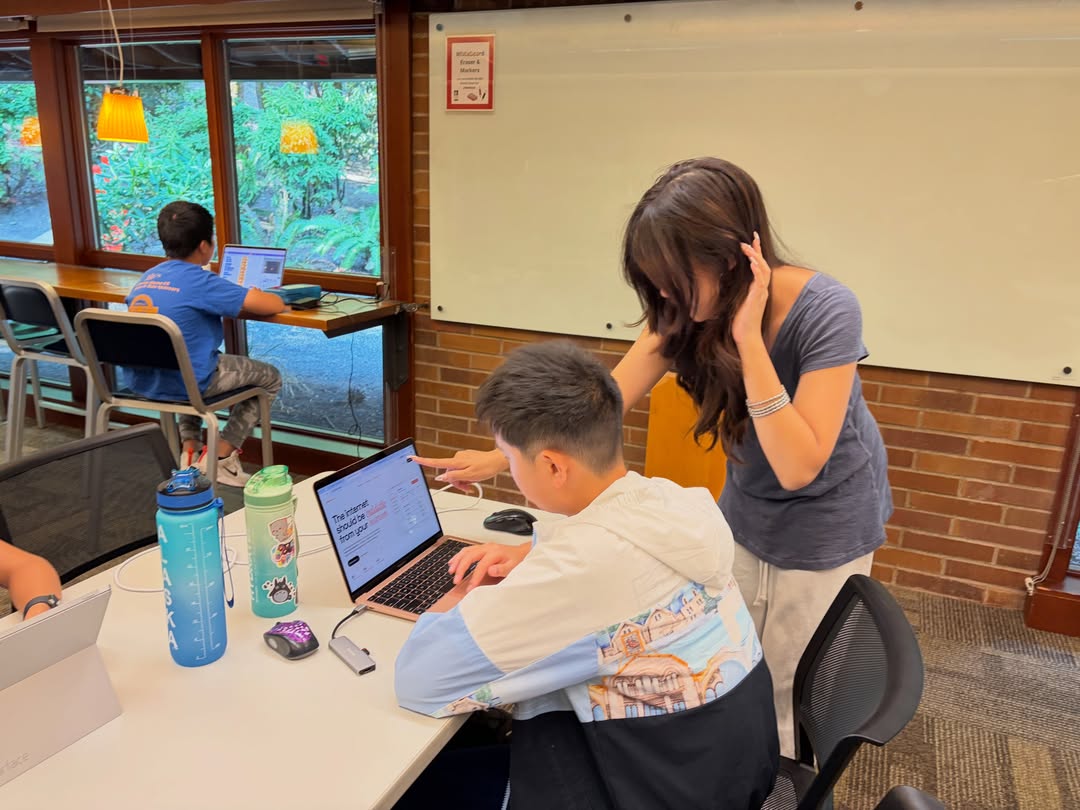 A mentor pointing at the SparkCloud page open on a student's laptop